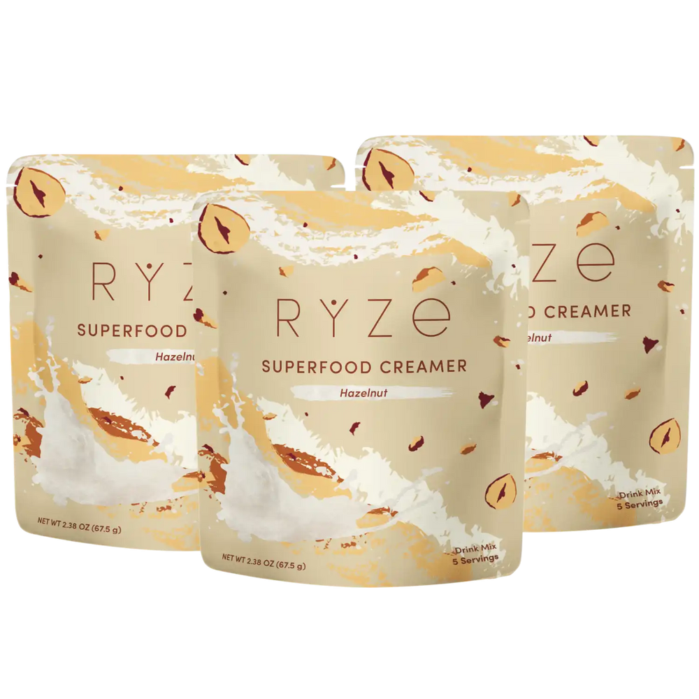 Three stand-up pouches of RYZE Superfood Creamer in Hazelnut flavor, arranged in a fan shape on a plain white background.