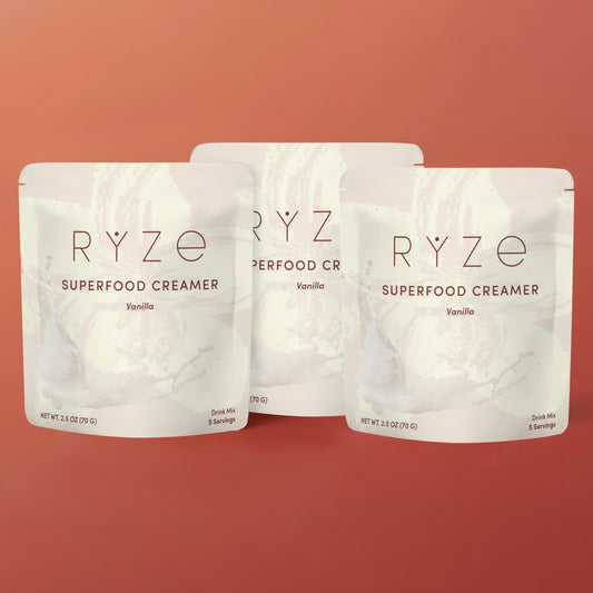 Three packages of RYZé Superfood Creamer on a red background
