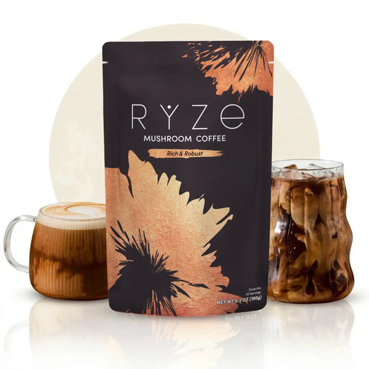 A stand-up pouch of RYZE Mushroom Coffee, Rich & Robust flavor, styled with a glass mug of iced coffee and a glass of iced coffee on a white reflective surface.
