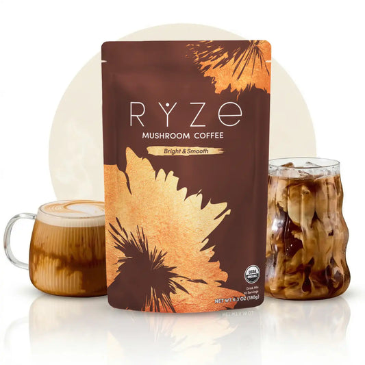 A stand-up pouch of RYZE Mushroom Coffee in the Bright & Smooth flavor, displayed between two glass mugs of coffee on a reflective white surface against a light beige circular backdrop.