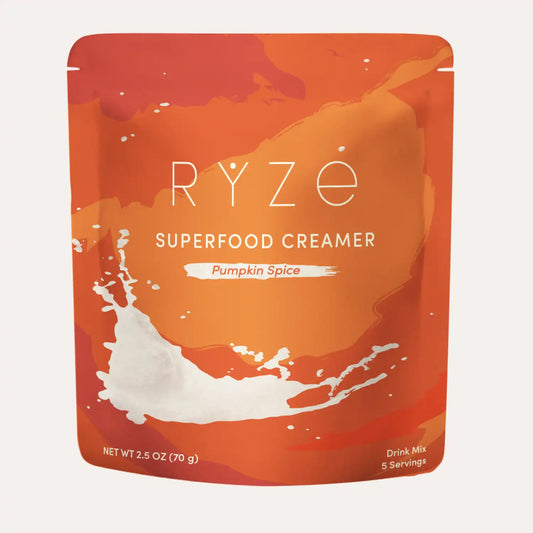 A stand-up pouch of RYZE Superfood Creamer in Pumpkin Spice flavor, featuring a vibrant orange and red design with a white milk splash graphic on a light off-white background.