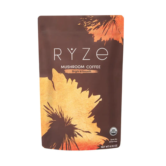 A stand-up pouch of RYZE Mushroom Coffee on a plain white background. The packaging is dark brown with large abstract orange and gold leaf-like shapes and white text reading 'RYZE' and 'MUSHROOM COFFEE'.