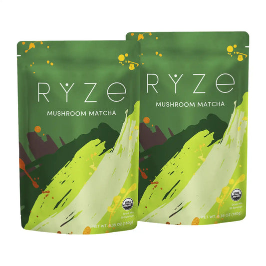 Two pouches of RYZE Mushroom Matcha tea displayed side-by-side on a plain white background. The packaging features a green and yellow-green abstract brushstroke design with small orange splatters.