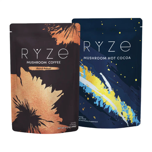 Two stand-up pouches of RYZE coffee and cocoa products on a plain white background. The left pouch shows Mushroom Hot Cocoa in brown with copper and black floral brushstroke graphics and reads 'RYZE MUSHROOM COFFEE Rich & Robust.