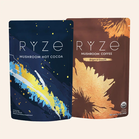 Two stand-up pouches of RYZE coffee and cocoa products on a light beige background. The left pouch is dark navy blue with yellow, white, and blue brushstroke artwork and reads 'RYZE MUSHROOM HOT COCOA.