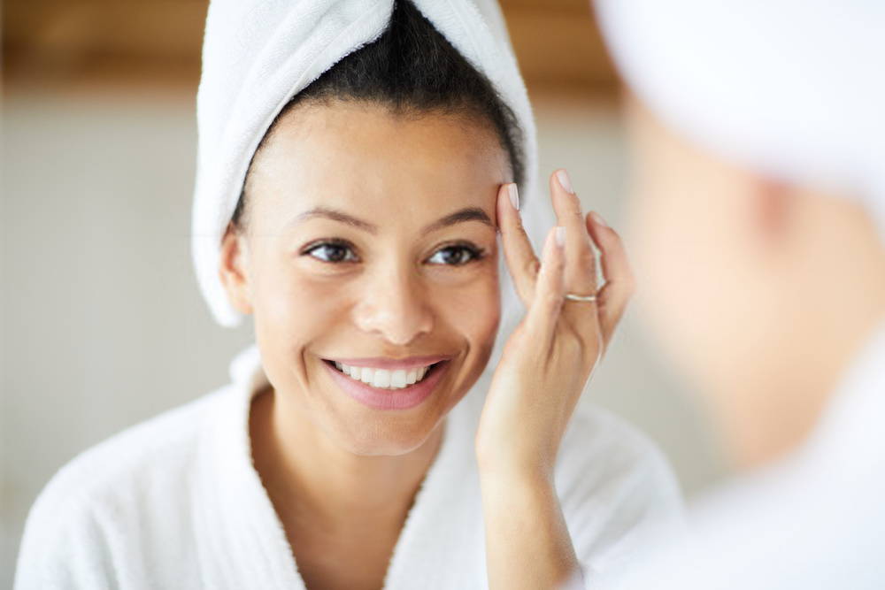young woman looking in mirror as she applies face cream