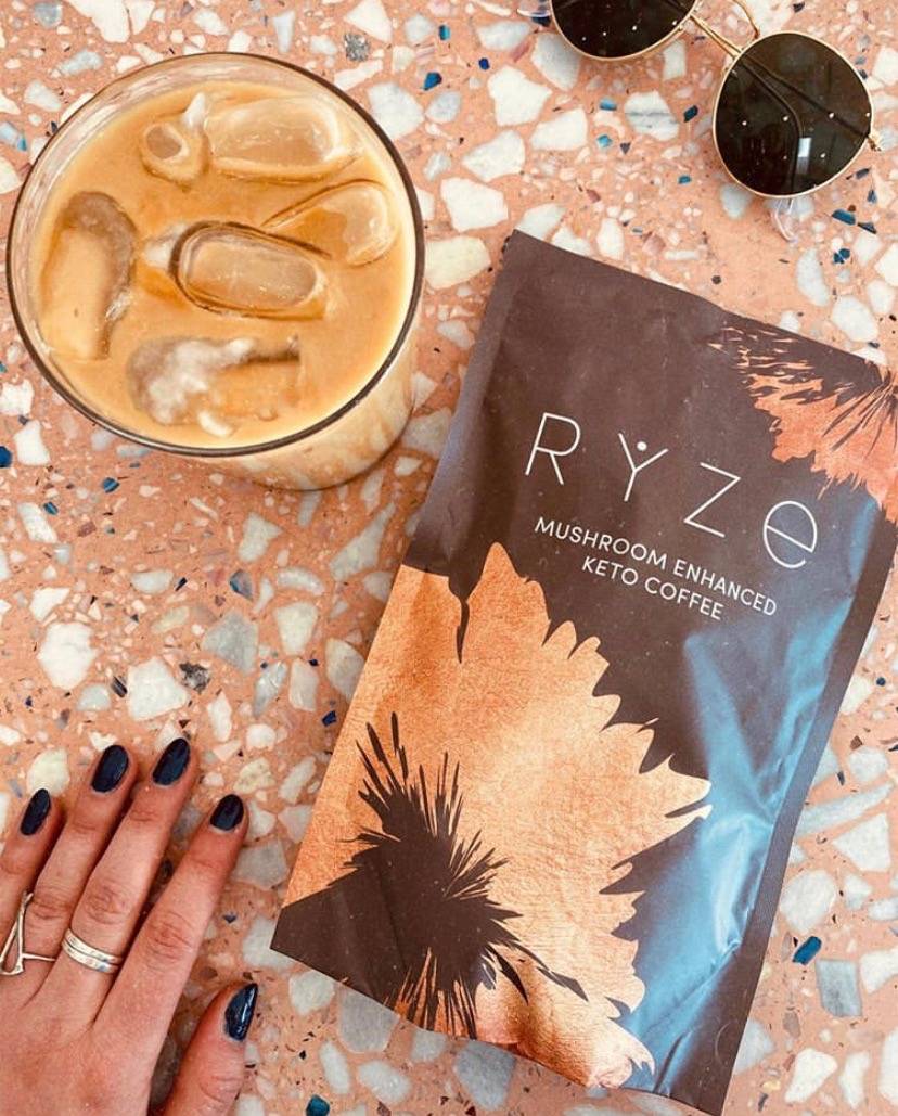 Bag of RYZE mushroom coffee with glass of iced coffee and sunglass on the table