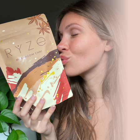 Person holding a Ryze Mushroom Chai package outdoors.