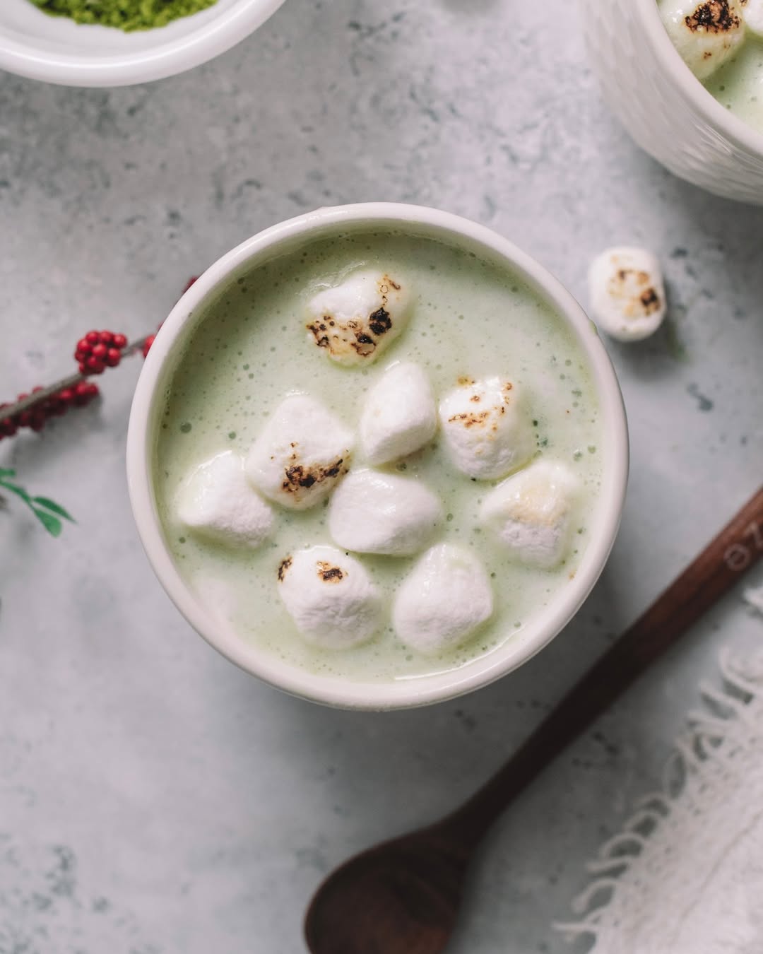 A cup of green matcha latte topped with toasted marshmallows.