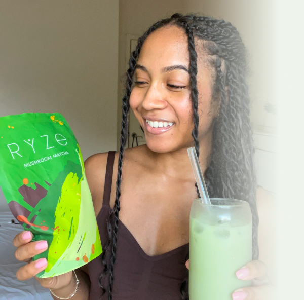 Person holding a Ryze Mushroom Matcha package and a glass of green drink.