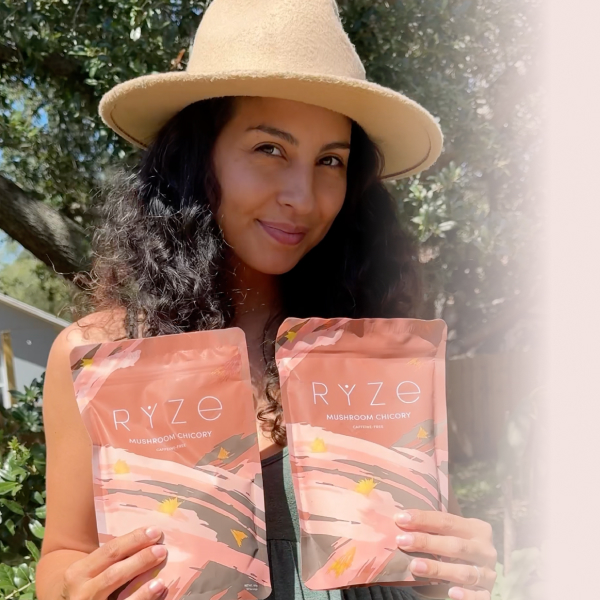 Person holding two Ryze Mushroom Chicory packages outdoors.