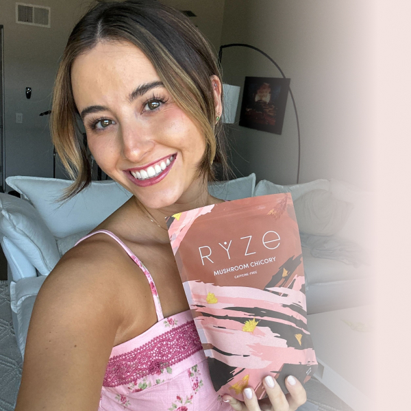 Person smiling and holding a Ryze Mushroom Chicory package indoors.