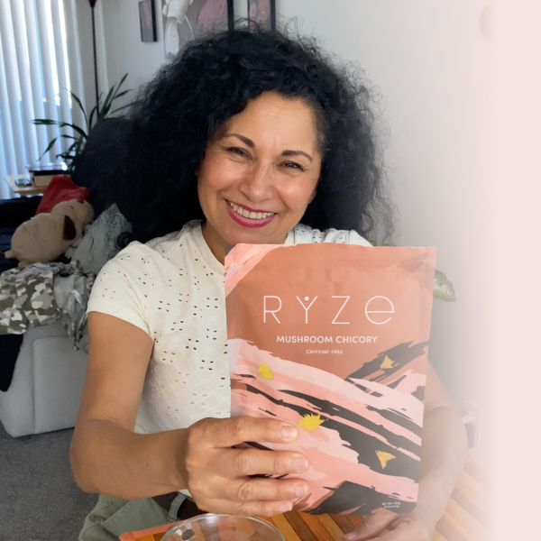 Person smiling and holding a Ryze Mushroom Chicory package.
